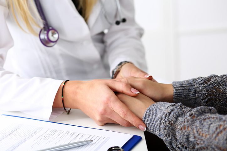 Friendly female doctor hold patient hand in office during while discussing types of treatments for depression