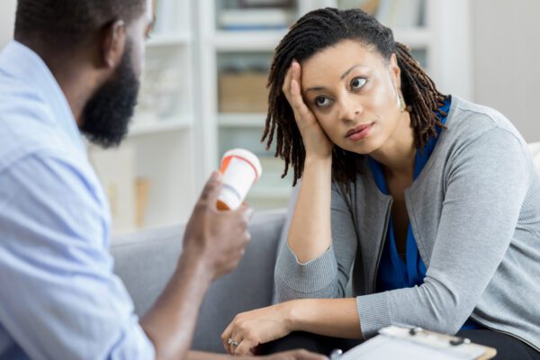 Male mental health professional holds a container of anti depressant medication. The patient is looking at the mental health professional with an uncertain expression on her face as she is wondering What to Do When Antidepressants Don’t Work