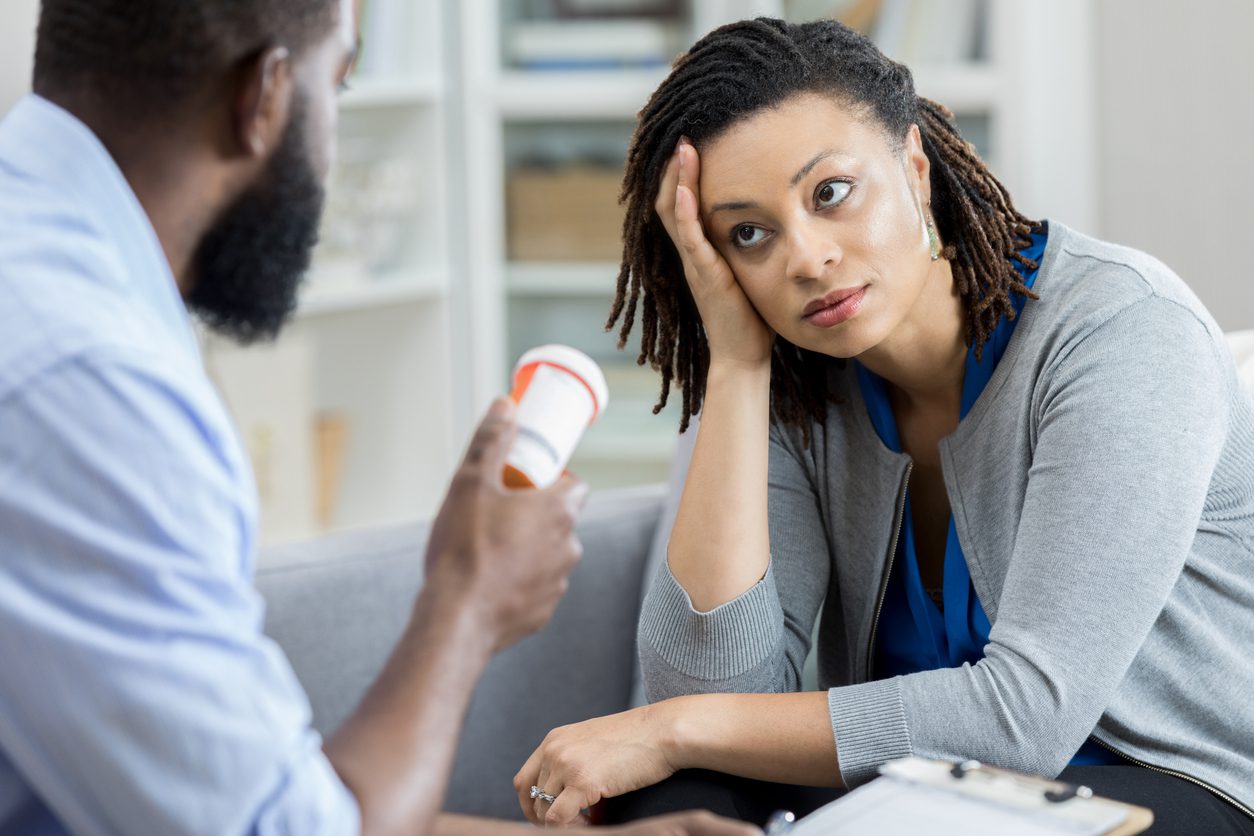 Male mental health professional holds a container of anti depressant medication. The patient is looking at the mental health professional with an uncertain expression on her face as she is wondering What to Do When Antidepressants Don’t Work